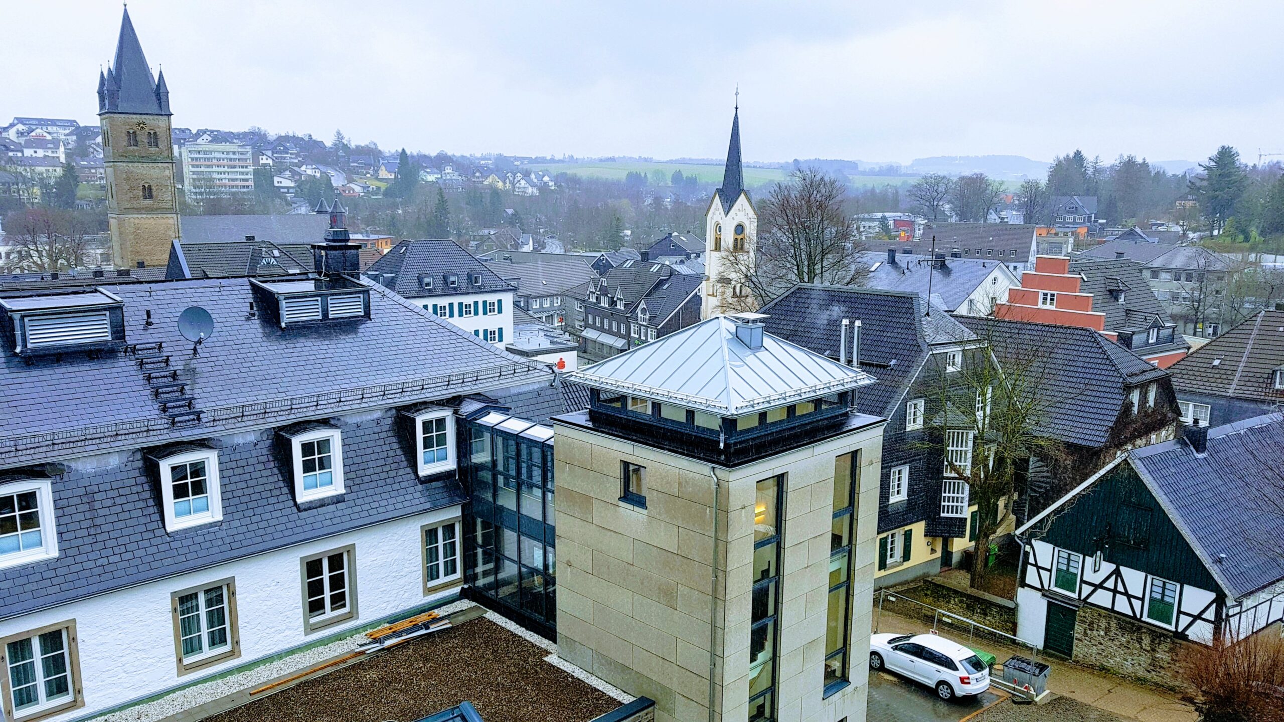 Stadtansicht mit modernem Gebäudeteil und verglastem Dachaufsatz.