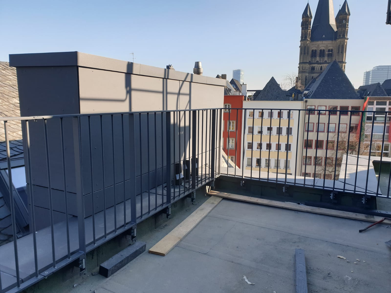 Geländer – Dachterrasse Hotel Metallgeländer auf einer Hotel-Dachterrasse mit Blick über die Stadt und eine Kirche, Montagesituation