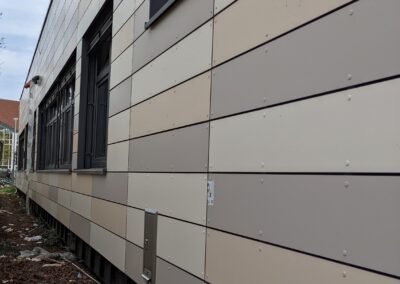 Hartfaserplatten-Fassade in verschiedenen Naturtönen an einem Schulgebäude, Seitenansicht
