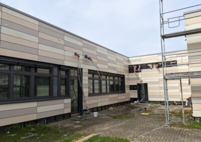 Fassadensanierung eines Schulgebäudes mit horizontalen Hartfaserplatten in Brauntönen, Innenhofansicht