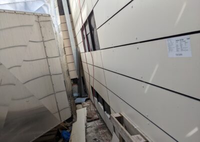 Hartfaserplatten-Fassade in Montage mit freiliegender Unterkonstruktion und teilweise gesetzten Paneelen