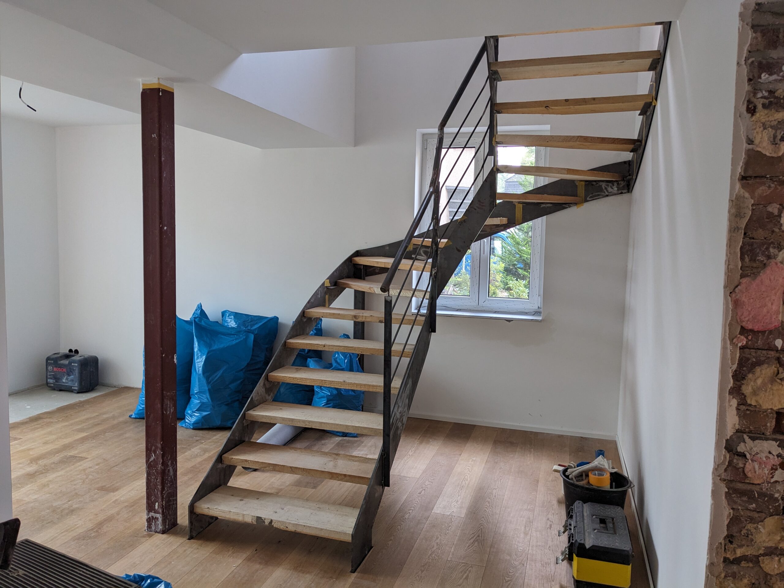 Gewendelte Treppe mit schlichtem Geländer, Holzstufen und gelaserten Stahlblechwangen