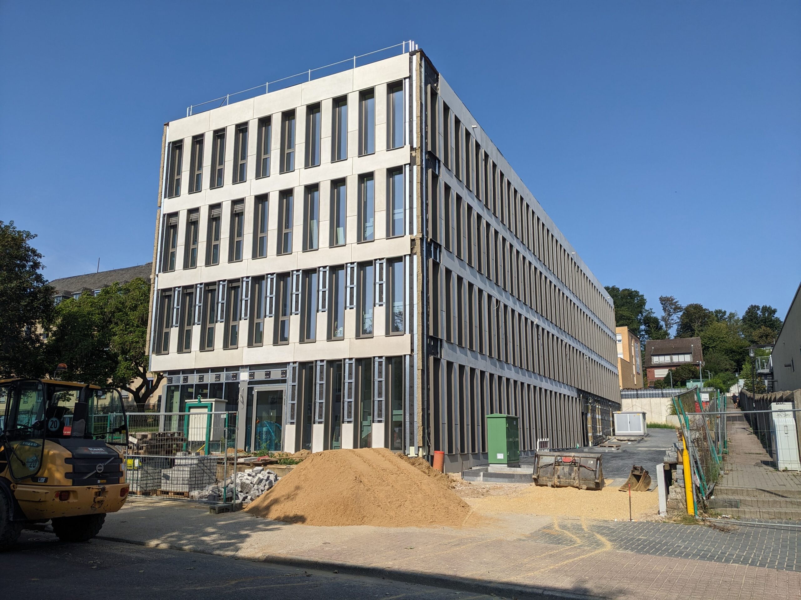 Gebäude mit Steinkompositfassade in Montage, vertikale Elemente und sichtbare Unterkonstruktion