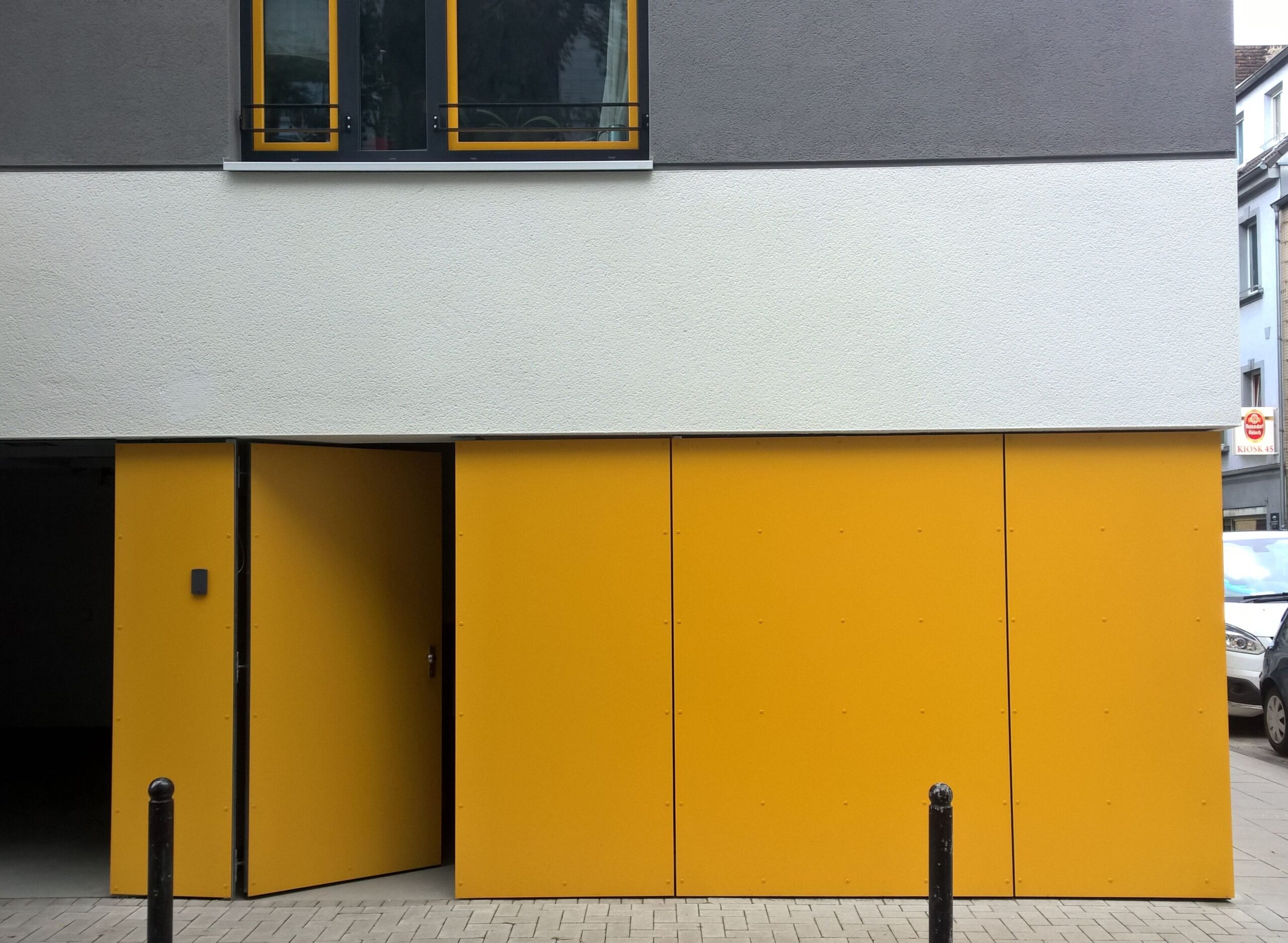Gelbe Fassadenplatten als Verkleidung im Eingangs- und Garagenbereich eines Mehrfamilienhauses