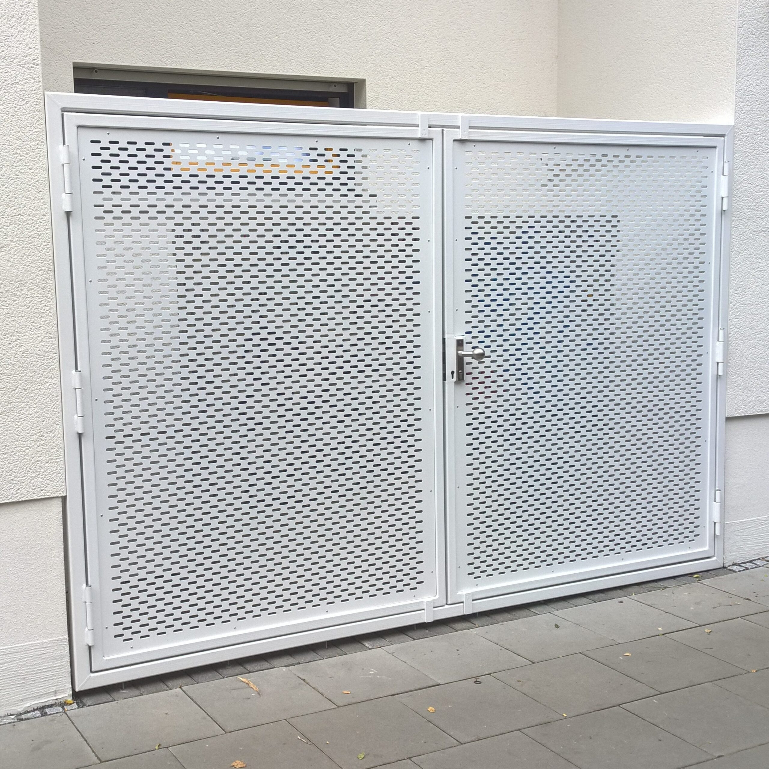 Zweiflügeliges weißes Stahltor mit Lochblechfüllung an der Straßenrand